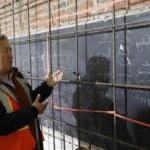 A man in construction vest stands before a blackboard